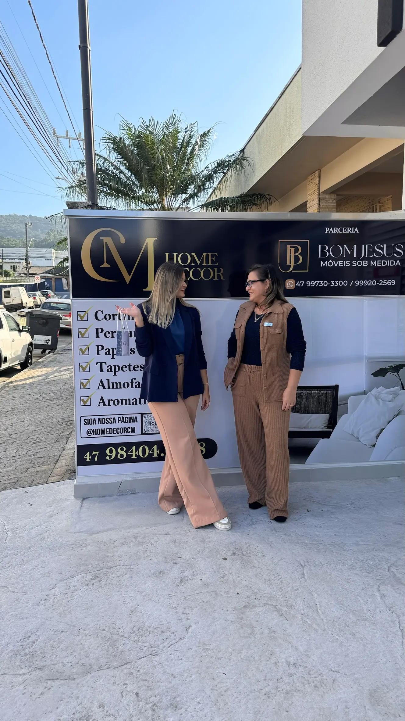 Equipe da CM Home Decor junto ao banner da parceria com a Bom Jesus Móveis