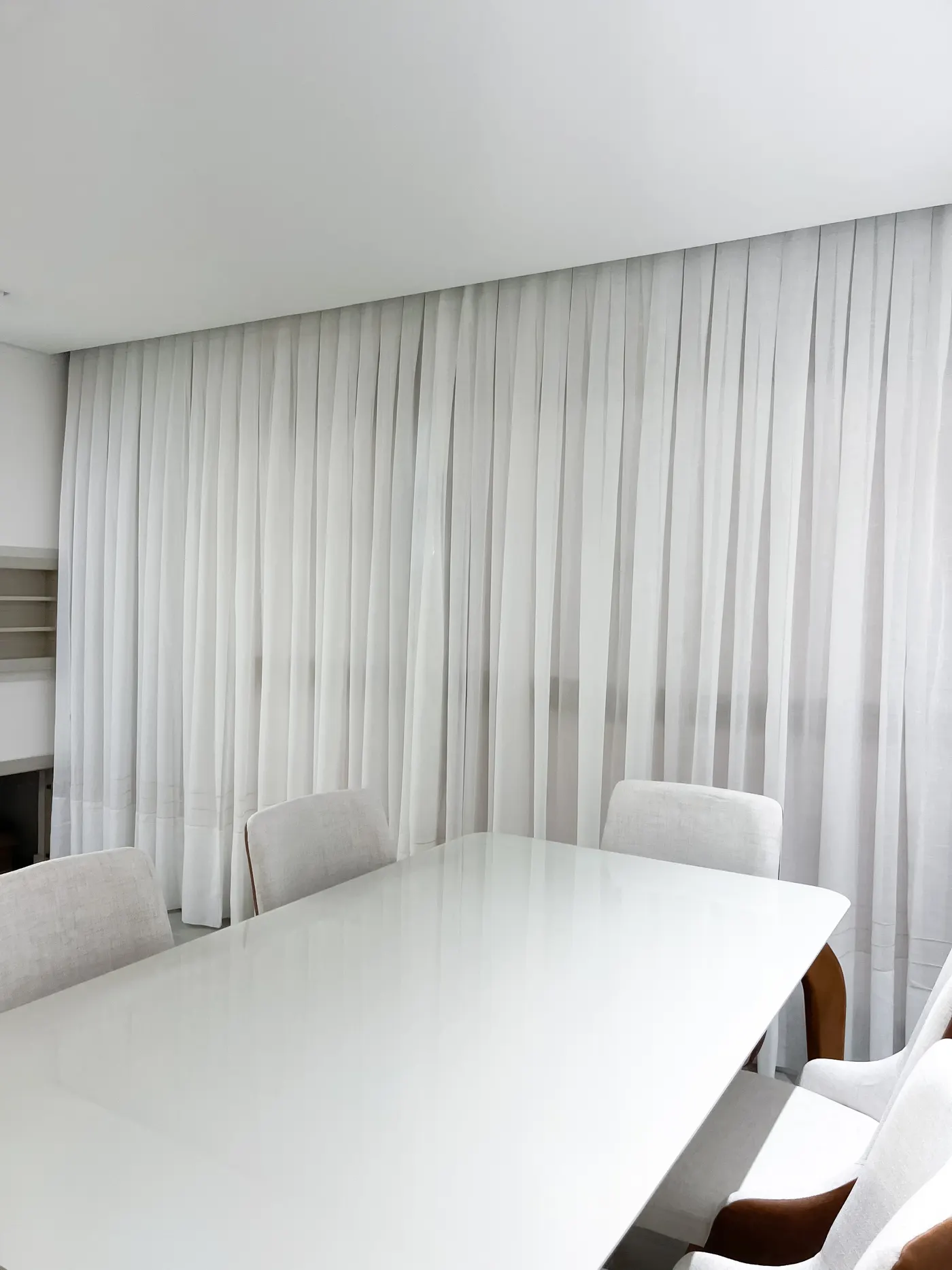 Sala de jantar com cortina branca e mesa clara