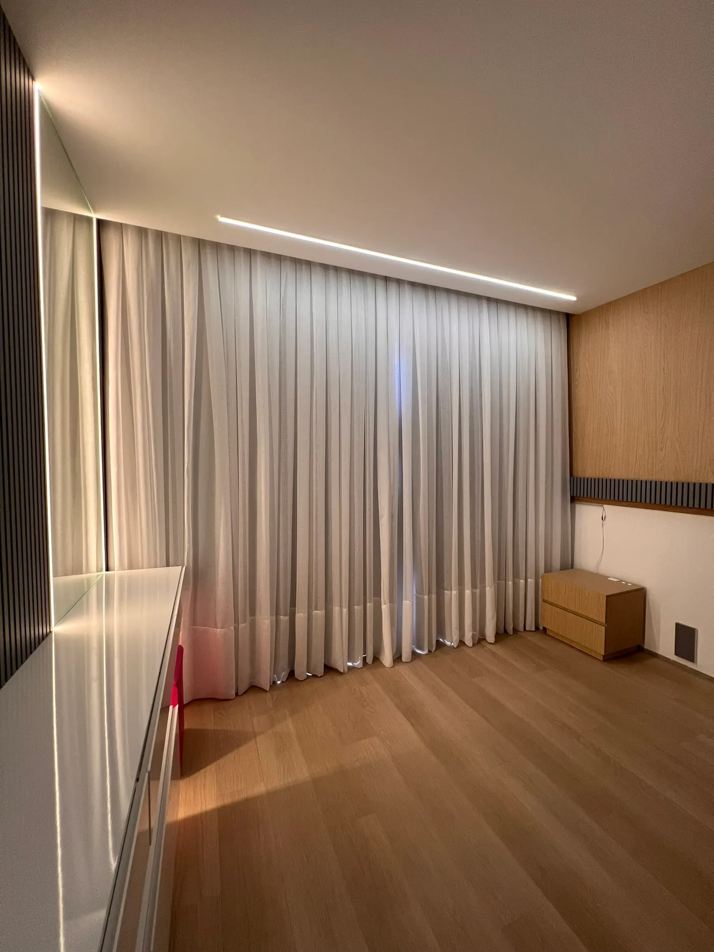 Quarto com cortina branca e painel de madeira